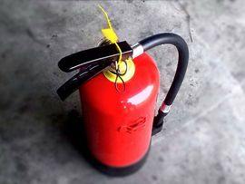 Rødt brann slokkingsapparat på grått gulv