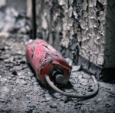 Utbrent gulv og vegger med rødt brannslokkningsapparat